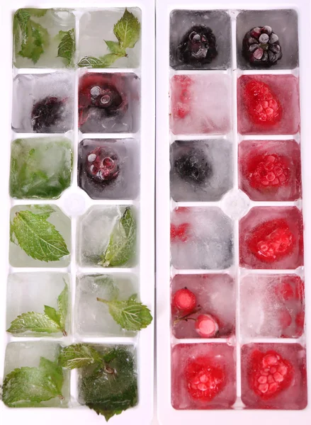 Cubos de hielo con bayas del bosque, hojas de menta en bandeja de cubo de hielo, primer plano — Foto de Stock