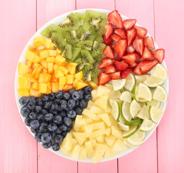 Frutas fatiadas no prato na mesa de madeira — Fotografia de Stock