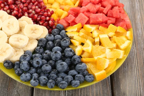 Frutas en rodajas en plato sobre mesa de madera — Foto de Stock