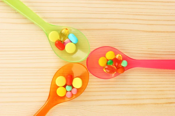 Plastic spoons with color pills — Stock Photo, Image