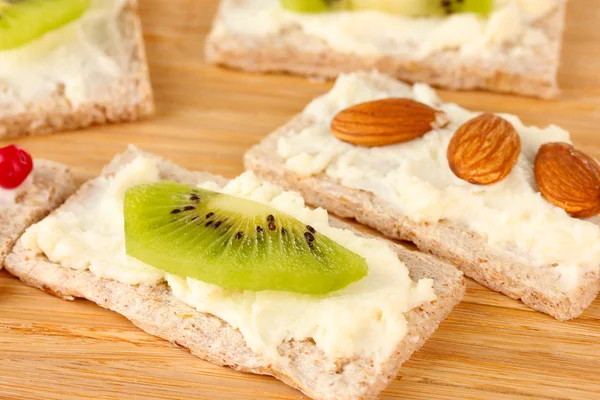 Canapés savoureux au fromage, kiwi et canneberge, amande, sur fond de bois — Photo