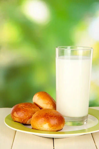 Bread rolls and glass of milk on wooden table on nature background — Stock Photo, Image