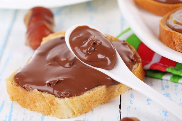 Pão com avelã de chocolate doce espalhado na placa na mesa — Fotografia de Stock