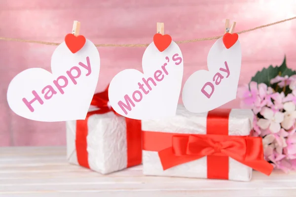 Happy Mothers Day message written on paper hearts with flowers on pink background — Stock Photo, Image