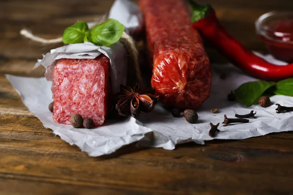 Leckere Salamiwurst und Gewürze auf Holzgrund — Stockfoto