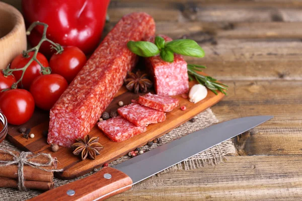 Leckere Salamiwurst und Gewürze auf Holzgrund — Stockfoto