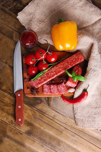 Salsicha de salame saboroso e especiarias em fundo de madeira — Fotografia de Stock