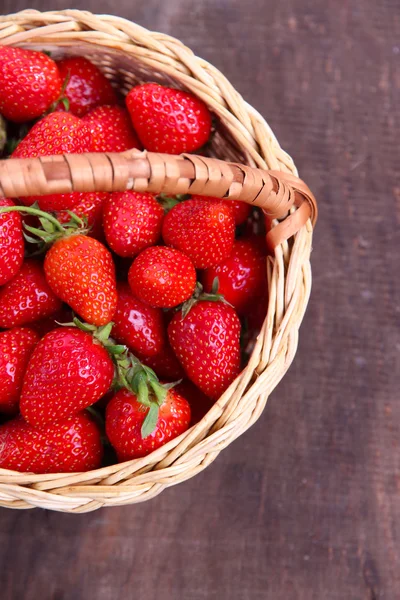 Ripe sweet strawberries in wicker basket on wooden background — Stock Photo, Image