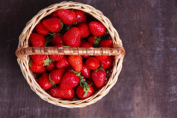 Ώριμα γλυκό φράουλες σε ψάθινο καλάθι σε ξύλινα φόντο — Φωτογραφία Αρχείου
