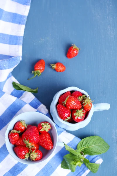 Fresas dulces maduras en tazas sobre fondo de madera de color — Foto de Stock