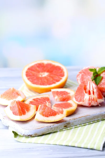 Ripe grapefruits on cutting board, on wooden table, on light background — Stock Photo, Image