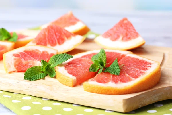 Mogen grapefrukt på skärbräda, på träbord, på ljus bakgrund — Stockfoto