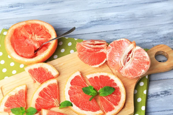 Ripe grapefruits on cutting board, on wooden table, on light background — Stock Photo, Image