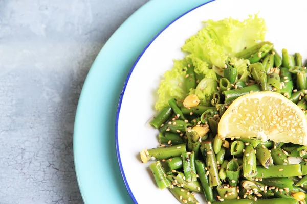 Renk ahşap zemin üzerine yeşil fasulye ve mısır, tabakta susam, salata — Stok fotoğraf
