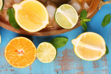 farklı dilimlenmiş sulu narenciye meyve tepsisi, mavi ahşap masa üstünde buz ile