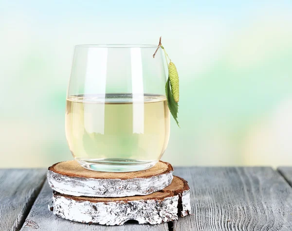 Glass of fresh birch sap on a wooden table on nature background — Stock Photo, Image