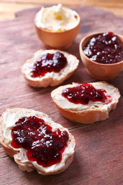 Vers brood met zelfgemaakte boter en kreken van zwarte jam op houten achtergrond — Stockfoto