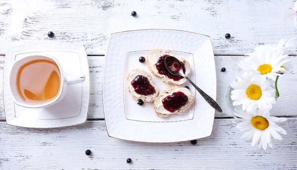 Verse toast met zelfgemaakte boter en kreken van zwarte jam op houten achtergrond — Stockfoto