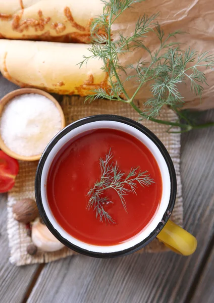 Sumo de tomate caseiro na caneca a cores, pães, especiarias e tomates frescos no fundo de madeira — Fotografia de Stock