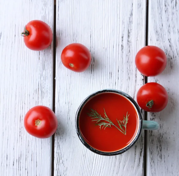 Sumo de tomate caseiro na caneca a cores e tomates frescos no fundo de madeira — Fotografia de Stock