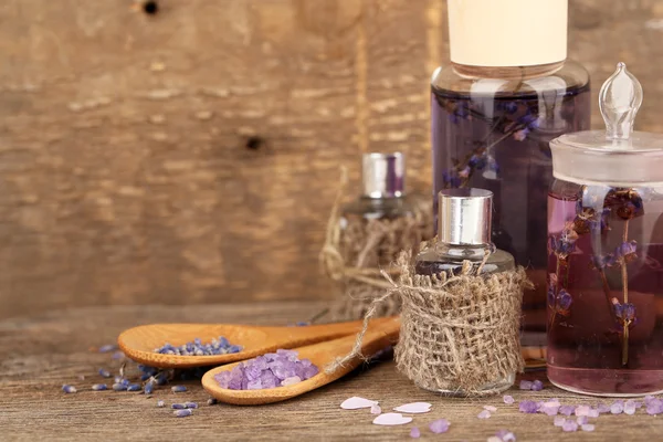 Wellness-Stillleben mit Lavendelöl und Blumen auf Holztisch — Stockfoto