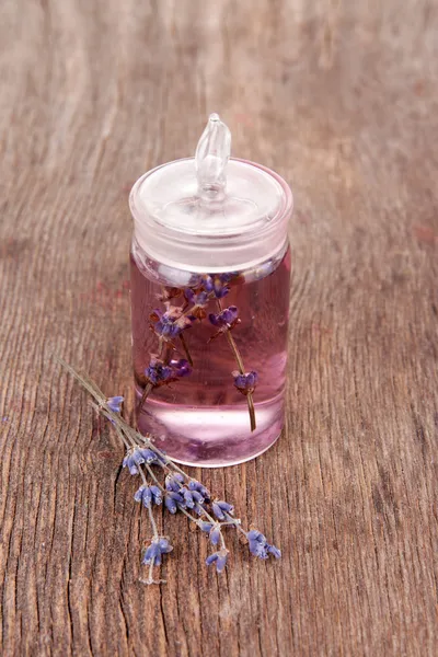 Lavender oil with flowers on wooden table — Stock Photo, Image