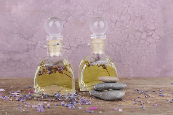 Bodegón Spa con aceite de lavanda y flores sobre mesa de madera, sobre fondo rosa —  Fotos de Stock