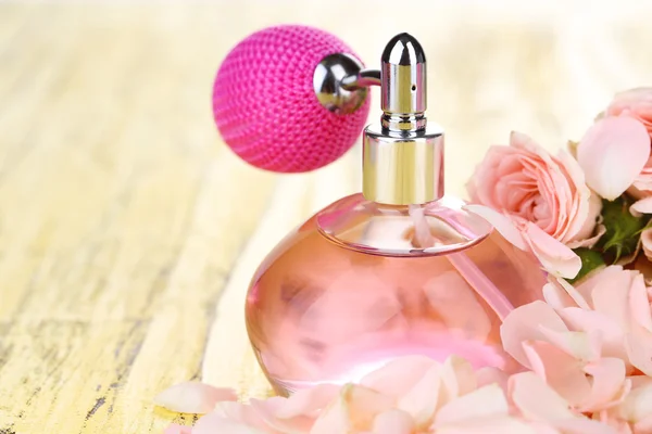 Perfume bottle with petals on table close-up — Stock Photo, Image