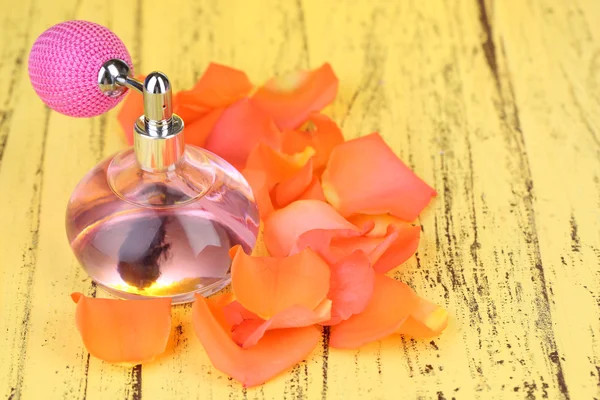 Parfumfles met bloemblaadjes op tabel close-up — Stockfoto