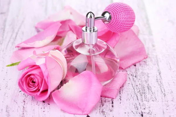 Frasco de perfume con pétalos de rosas en primer plano de la mesa — Foto de Stock