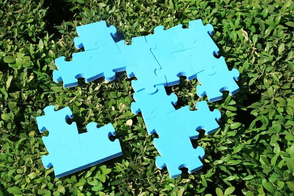Puzzle kousky na zelené trávě pozadí. koncept zelených ploch — Stock fotografie