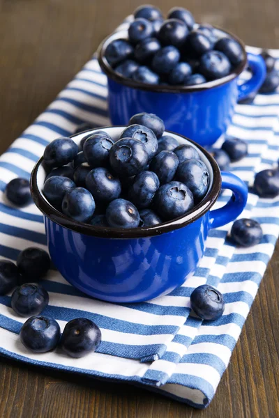 Läckra blåbär i koppar på tabell närbild — Stockfoto