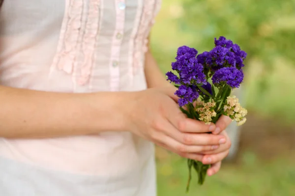 Flores silvestres em mãos de menina no fundo natural — Fotografia de Stock