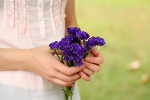 Дикі квіти в руках дівчини на природному тлі — стокове фото