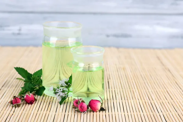 Aceite esencial con diferentes plantas medicinales, sobre fondo de madera — Foto de Stock