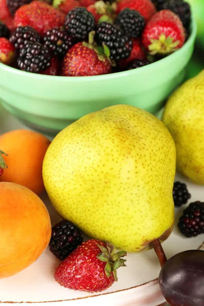 Las frutas maduras y las bayas en un tazón en la mesa de cerca —  Fotos de Stock