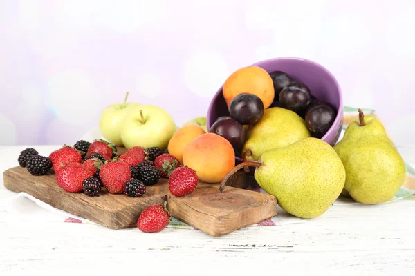 Zralé ovoce v míse a bobule na stole na světlé pozadí — Stock fotografie