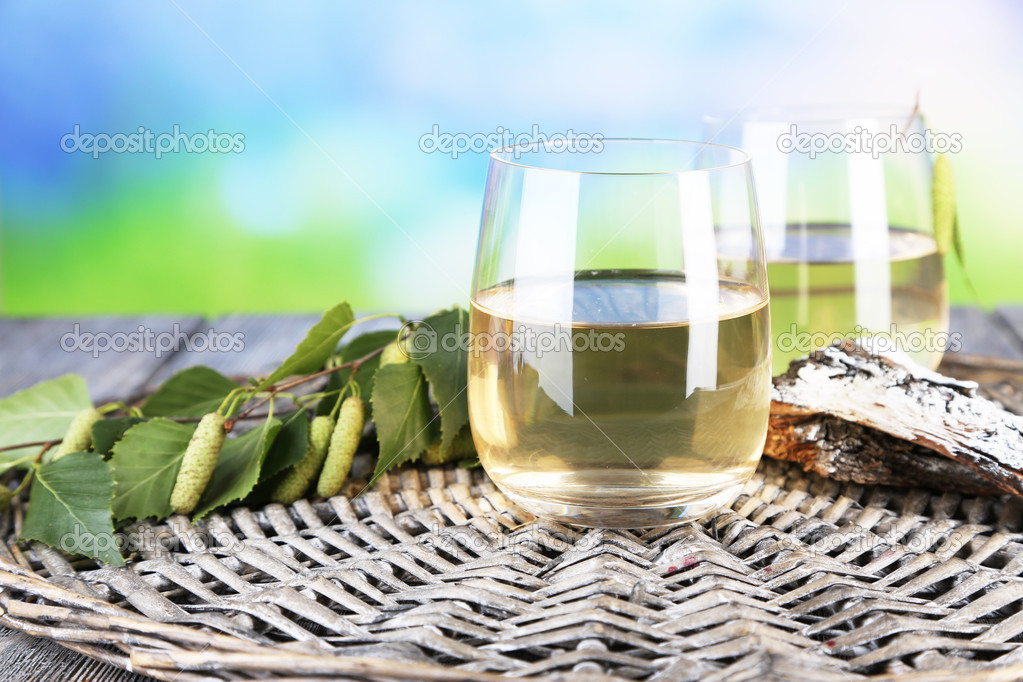 Glass of fresh birch sap on a wooden table on nature background