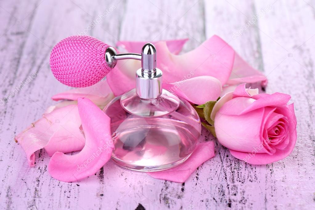 Perfume bottle with roses petals on table close-up