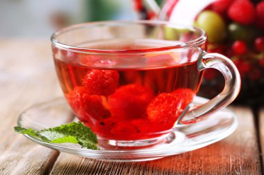 Yabani çilek cam bardakta parlak zemin üzerine ahşap masa ile kırmızı meyve çayı