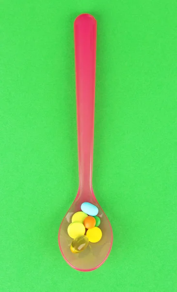 Cucchiaio di plastica con pillole di colore — Foto Stock