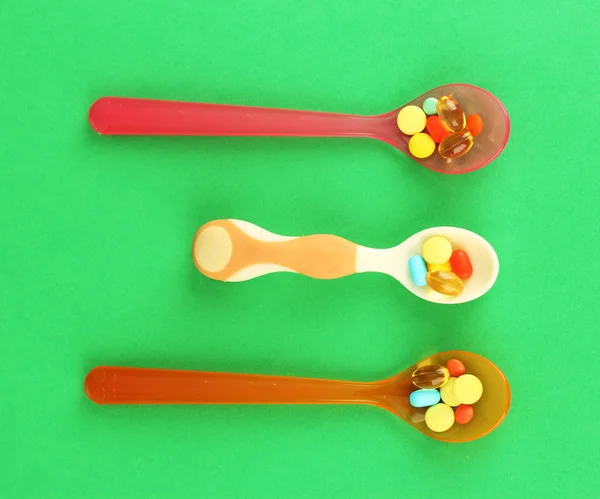 Plastic spoons with color pills — Stock Photo, Image