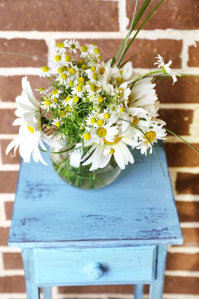 Beautiful bouquet of daisies in vase, on stand  on bricks background — Stock Photo, Image