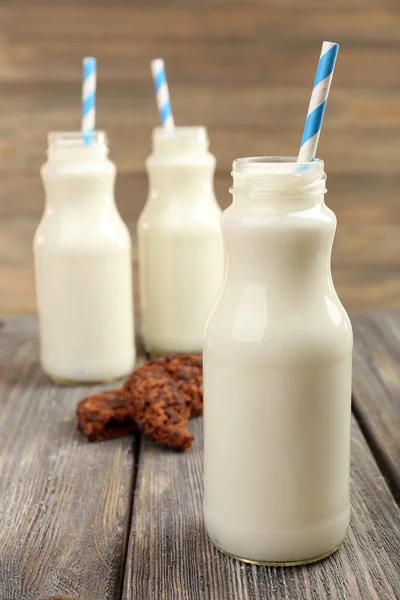 Mléko v lahvích s papírovými brčka na stole — Stock fotografie
