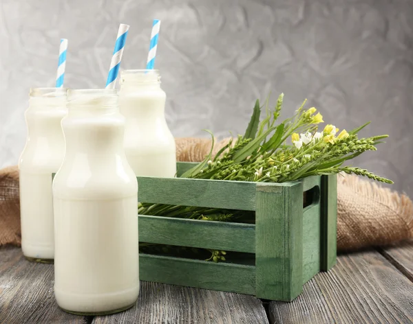 Mjölk i flaskor med papper strån på bord — Stockfoto