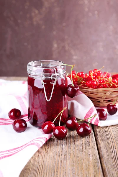 Jam in glazen pot op tafel, bessen close-up — Stockfoto