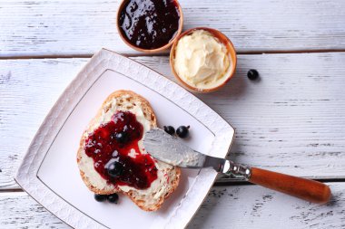 taze ekmek ile ev yapımı tereyağı ve blackcurrant jam hafif ahşap zemin üzerinde plaka üzerinde