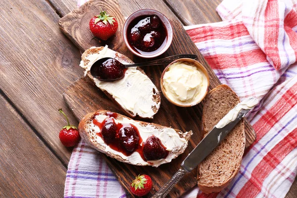 Fresh toast with homemade butter and strawberry jam on wooden background — Stock Photo, Image