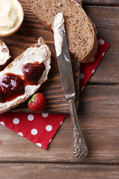 Verse toast met zelfgemaakte boter en strawberry jam op houten achtergrond — Stockfoto