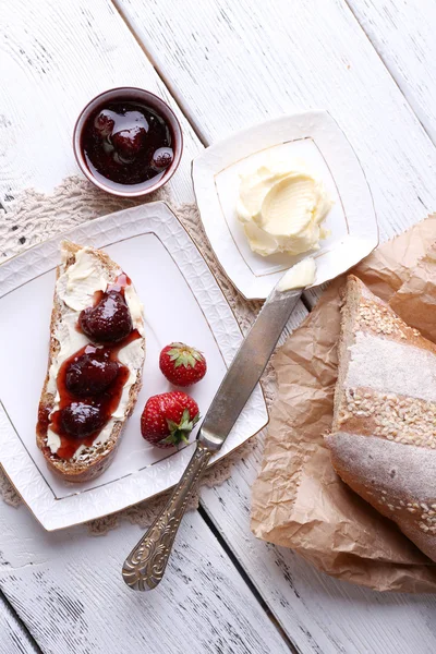 Čerstvé toasty s domácí máslem a jahodovým džemem, na světlé dřevěné pozadí — Stock fotografie